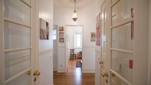 A hallway with white doors, a wooden floor, and a hanging light fixture. - Casa da Avenida III Lisboa (Lisbon)