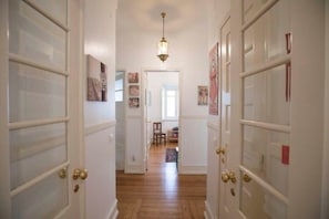 A hallway with white doors, a wooden floor, and a hanging light fixture.