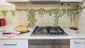 Una cocina con estufa a gas, un sándwich en la encimera y un cuenco de fresas.