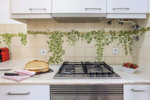 Una cucina con un fornello a gas, un panino sul bancone e una ciotola di fragole.