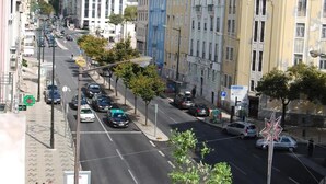 Una calle urbana con coches estacionados, edificios y un paso de peatones.