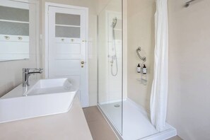 A bathroom with a white sink, a glass shower enclosure, and a white door with frosted glass panels.