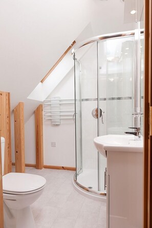Un baño moderno con cabina de ducha de vidrio, inodoro y lavabo blancos.
