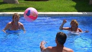 A swimming pool with people playing with a ball.