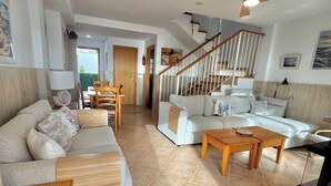 A spacious living area with a sofa set, a wooden coffee table, and a staircase leading to an upper level.