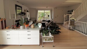 Een ruime woonkamer met een centraal eiland, een bank en een trap.