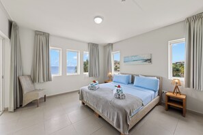 A bedroom with a bed, a chair, a bedside table, a lamp, and a painting. - Located directly on the beach, 4 person apartment with great sea view! (Blauw Baai)