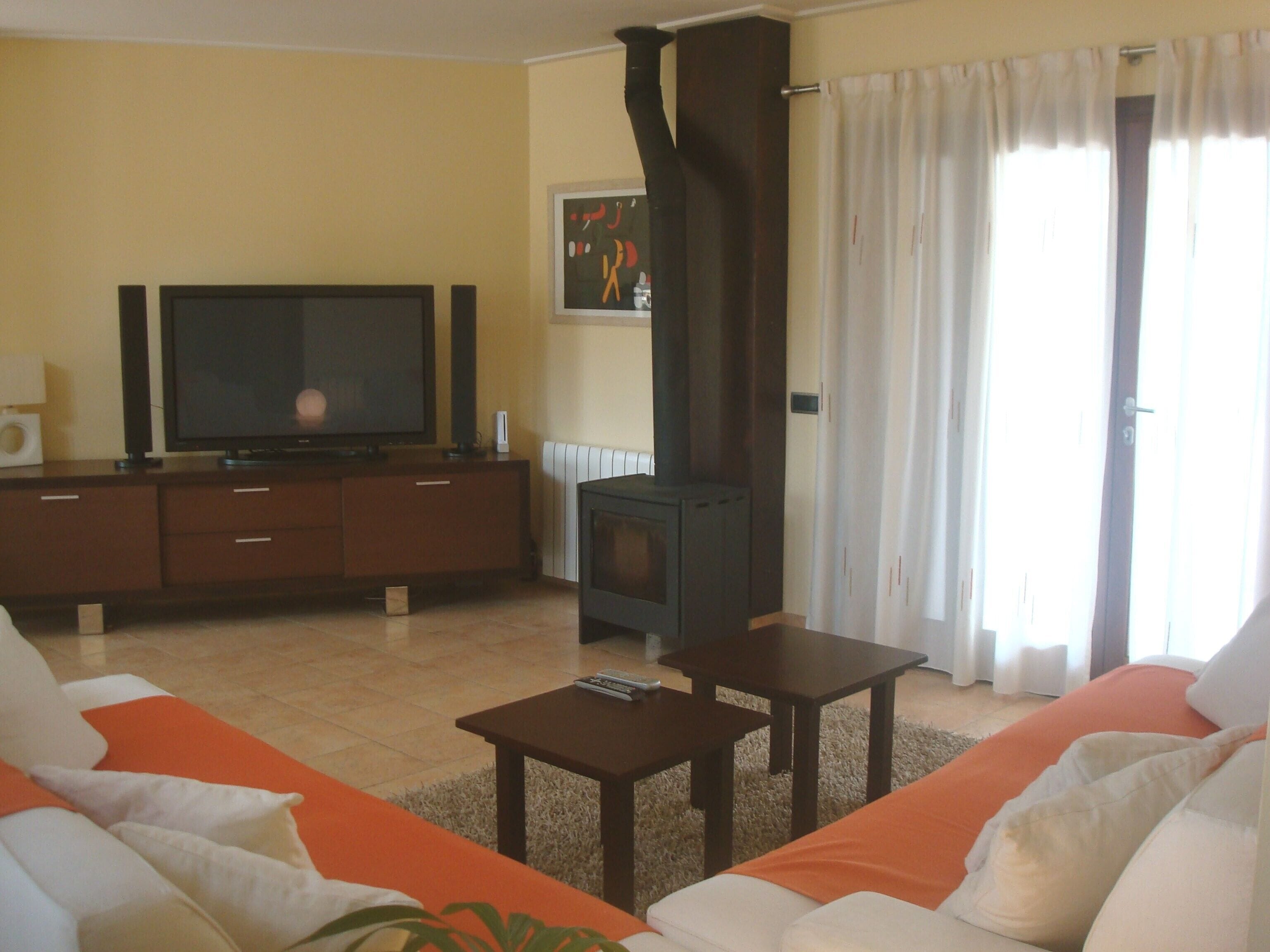 Una sala de estar con televisión, sofá, mesa de centro y chimenea.