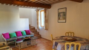 A cozy living room with a sofa, chairs, a dining table, and a staircase. - Gîte du Méou-Petite House-Laura (Lauris)