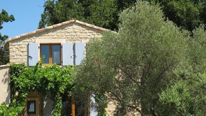 A stone building with a balcony and shutters, surrounded by greenery. - Gîte du Méou-Petite House-Laura (Lauris)