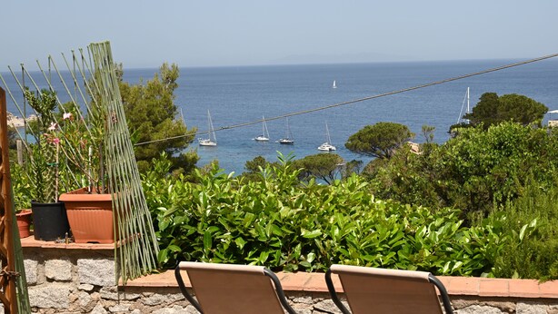 Eine Terrasse mit Stühlen mit Blick auf einen Yachthafen und Boote.