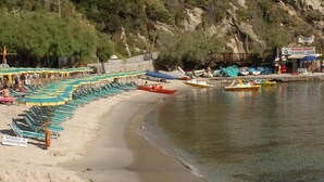 Ein Strand mit Liegestühlen und einer Reihe von Booten.