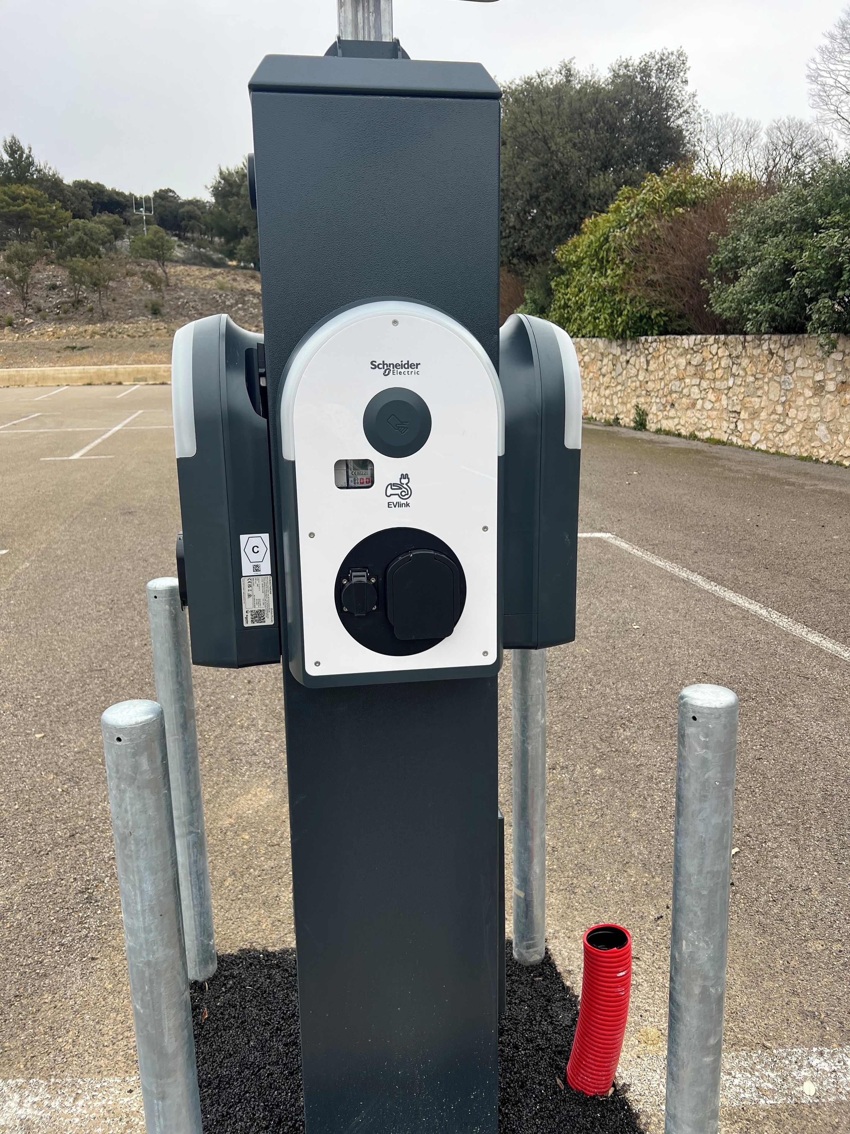 A charging station with a digital display, a hand symbol, and a plug.