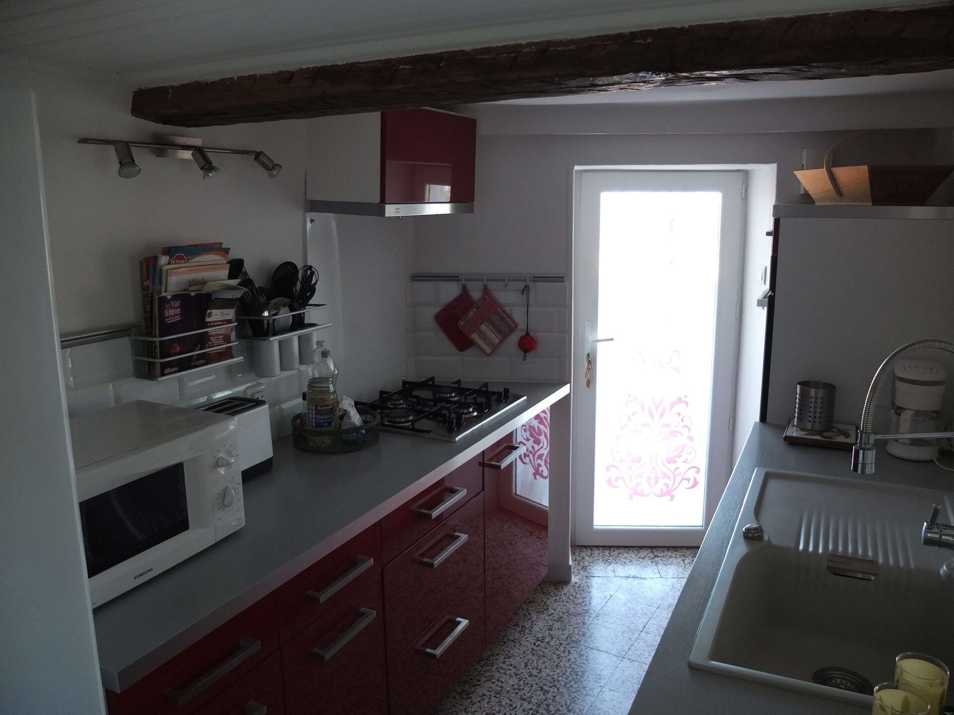 Cocina equipada con microondas, estufa y lavaplatos. Se observan armarios y una ventana con vistas.