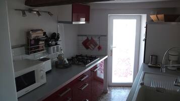 Cocina equipada con microondas, estufa y lavaplatos. Se observan armarios y una ventana con vistas.