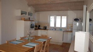 Una cocina compacta con armarios blancos, una mesa de comedor de madera y una ventana.