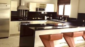 A modern kitchen with a central island, stainless steel appliances, and a window with blinds. - LUXURY CASA DEL VIRREY ESLAVA APARTMENT 304, INSID (CARTAGENA DE INDIAS)