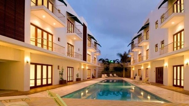 A hotel with a swimming pool, lounge chairs, and a wooden deck. - LUXURY CASA DEL VIRREY ESLAVA APARTMENT 304, INSID (CARTAGENA DE INDIAS)
