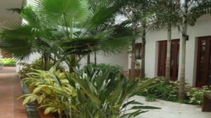 A pathway lined with plants and a bench, leading to a building with a white facade and red-framed windows. - LUXURY CASA DEL VIRREY ESLAVA APARTMENT 304, INSID (CARTAGENA DE INDIAS)