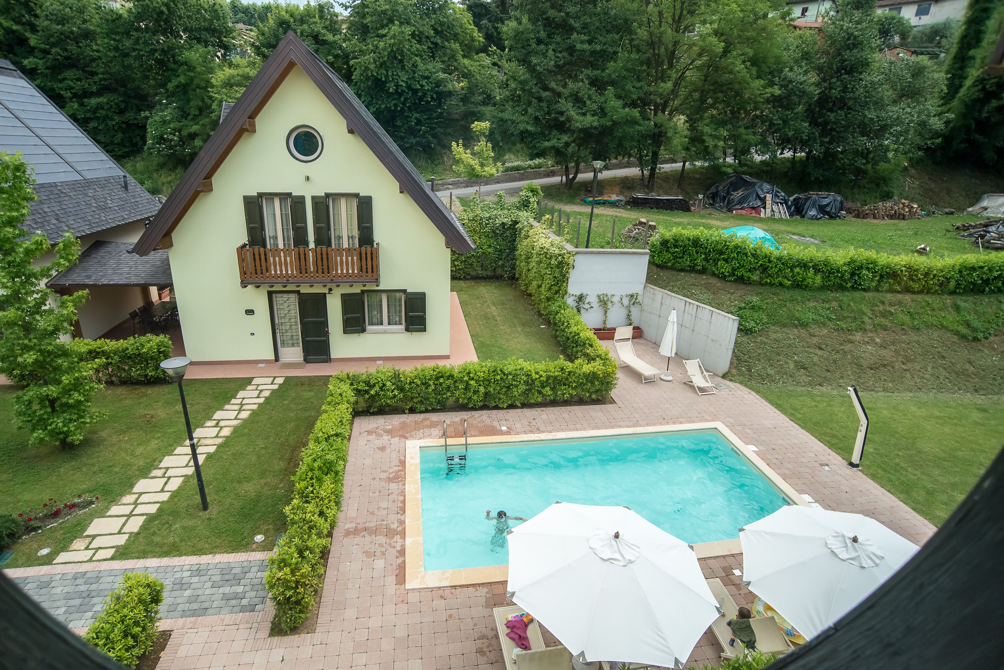 A house with a swimming pool, a balcony, and a well-maintained garden.