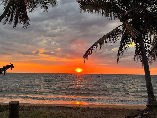 Ein Sonnenuntergang über dem Meer mit Palmen und Booten.