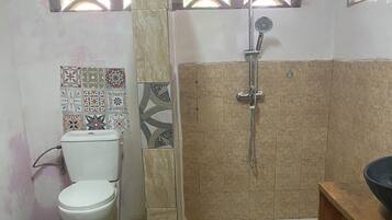 A bathroom with a toilet, shower, and sink.