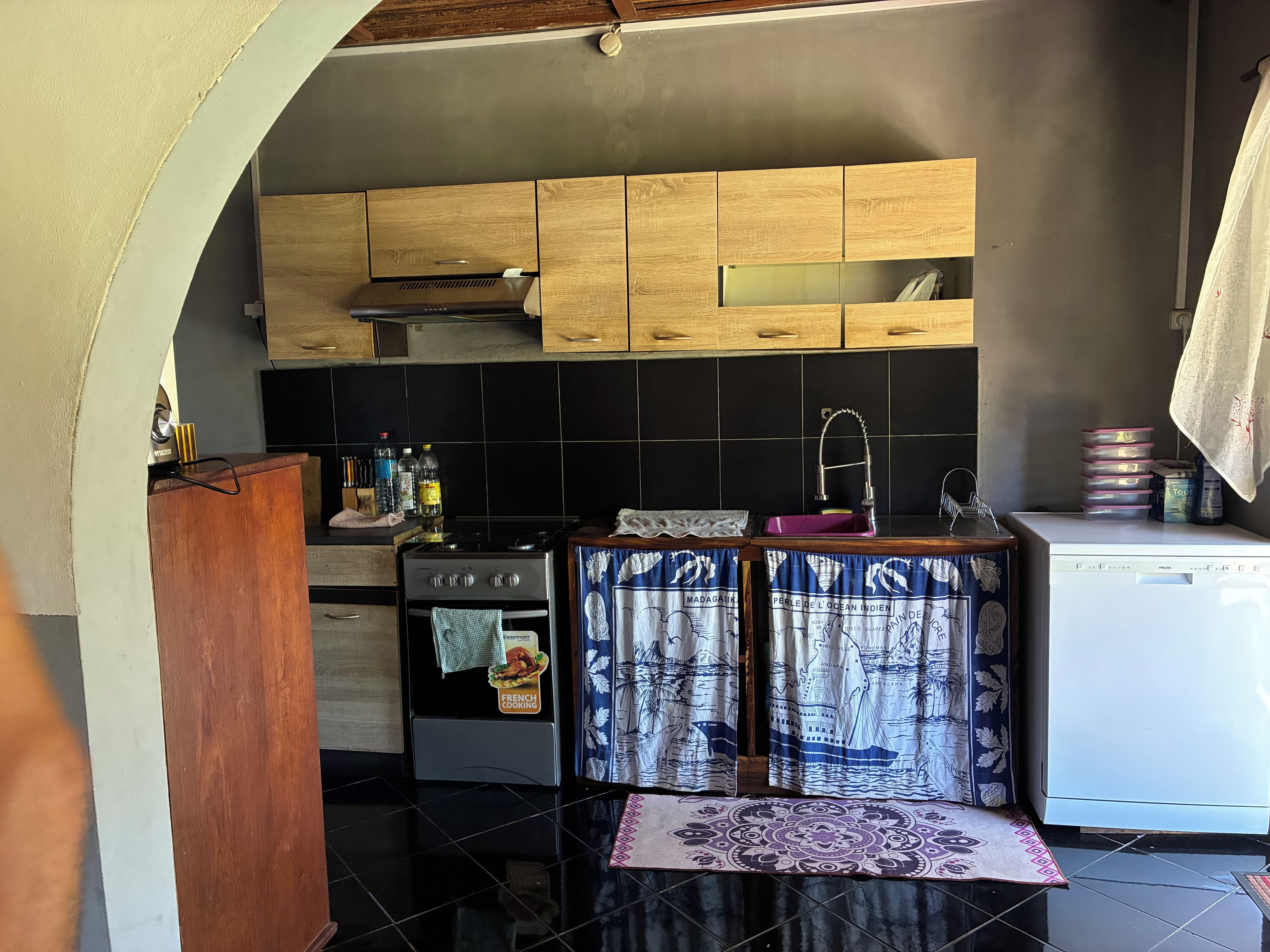 Una cucina compatta con mobili in legno, un fornello, un lavandino e una lavastoviglie.