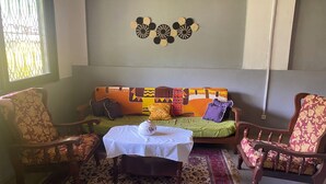 Un salon chaleureux avec un canapé, deux fauteuils, une table basse et un tapis à motifs.