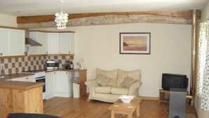 A compact living space with a kitchenette, a sofa, a television, and a dining area. - Fully Furnished 2 Bed Gite Situated In 3 Acres (Arné)
