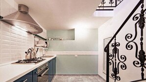 A modern kitchen with a gas stove, stainless steel range hood, and a marble floor. - TrastevereHome - Sales Rome (Roma)