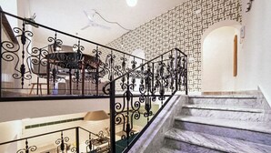 A staircase with ornate metal railings, a patterned wall, and a ceiling fan. - TrastevereHome - Sales Rome (Roma)