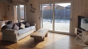 Un salon chaleureux avec un plancher en bois, un canapé, une table basse et un téléviseur.