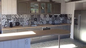 Une cuisine avec des carreaux décoratifs, des armoires en bois, un réfrigérateur en acier inoxydable et un plan de travail en bois.