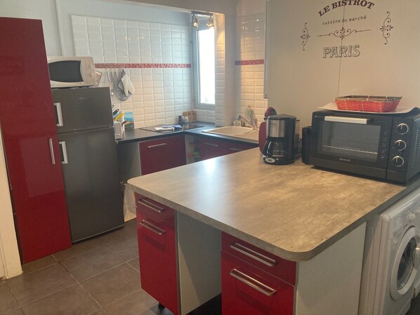 A compact kitchen with a refrigerator, microwave, coffee maker, and a washing machine.
