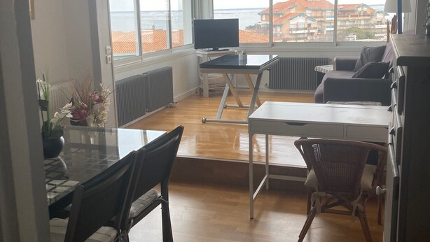 Un'ampia zona giorno con una grande finestra vista mare, un tavolo da pranzo con sedie, una televisione e un divano.