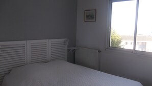 Una camera da letto con un letto, un termosifone, una finestra e un quadro appeso al muro.