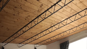 Un salon chaleureux avec un plafond en bois, un canapé, une table à manger avec des chaises et une vue sur l’extérieur.