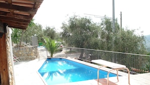 Une piscine rectangulaire avec un escalier en métal et une chaise longue blanche.