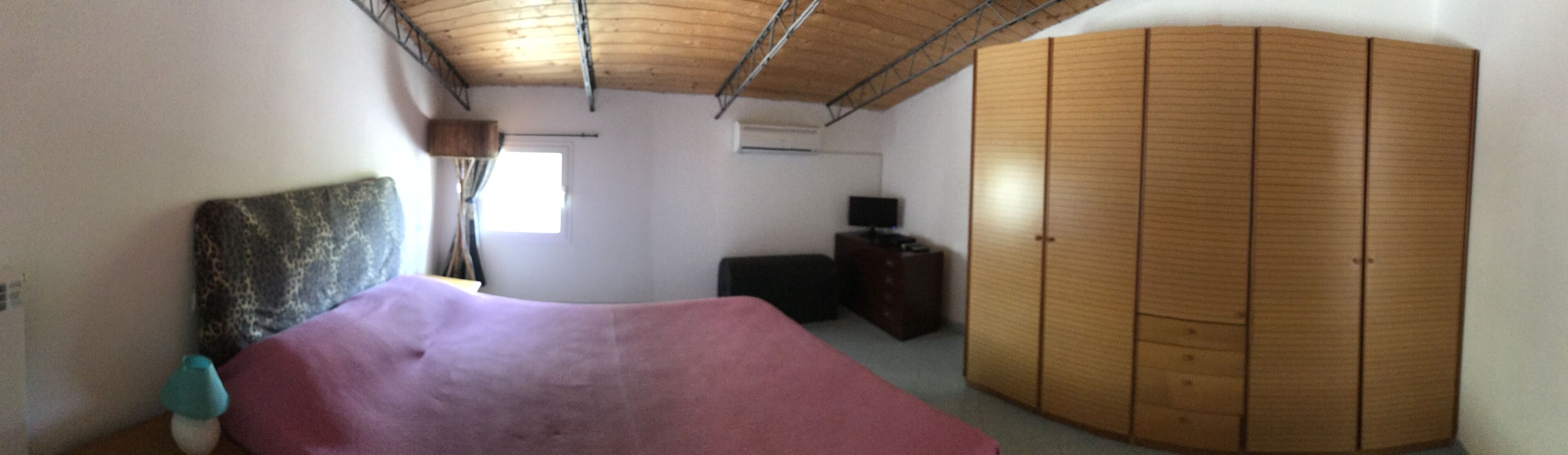 A bedroom with a bed, wardrobe, and a window.