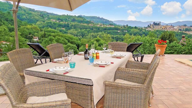 An outdoor dining area with wicker chairs and a table set for a meal, overlooking a scenic hillside view. - Casa Roc,  Private Pool, & Arguably Best View In Barga! WIFI. Walk to rest/bar (Barga)