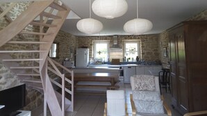 A modern kitchen with a central island, a wooden staircase, and pendant lighting. - Character house where one is at home (Plouhinec)