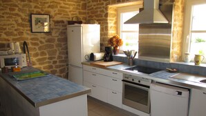 A kitchen with white cabinets, a stainless steel range hood, a built-in oven, and a window with a view of the outside. - Character house where one is at home (Plouhinec)