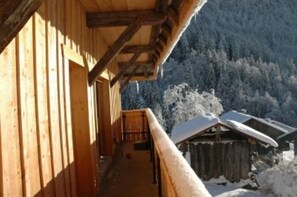 A wooden building with a balcony overlooking a snowy mountain landscape.
