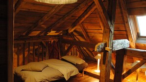 A wooden attic bedroom with a bed, a window, and a hanging light fixture. - Apartment in a chalet of character with ski access (Montriond)