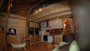A rustic wooden interior with a dining area, kitchen, and a television. - Apartment in a chalet of character with ski access (Montriond)