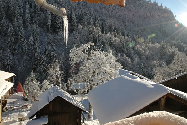 A snow-covered mountain landscape with wooden cabins and a wooden structure with a snow-covered roof.