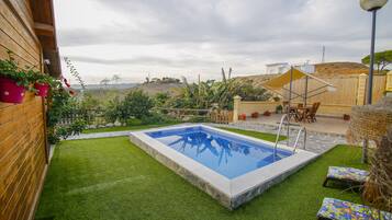 Relax by the pool surrounded by lush greenery and a scenic hilly landscape.