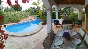 Un área de piscina al aire libre con una zona de comedor.