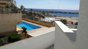 A rooftop pool with a view of the sea and a marina.
