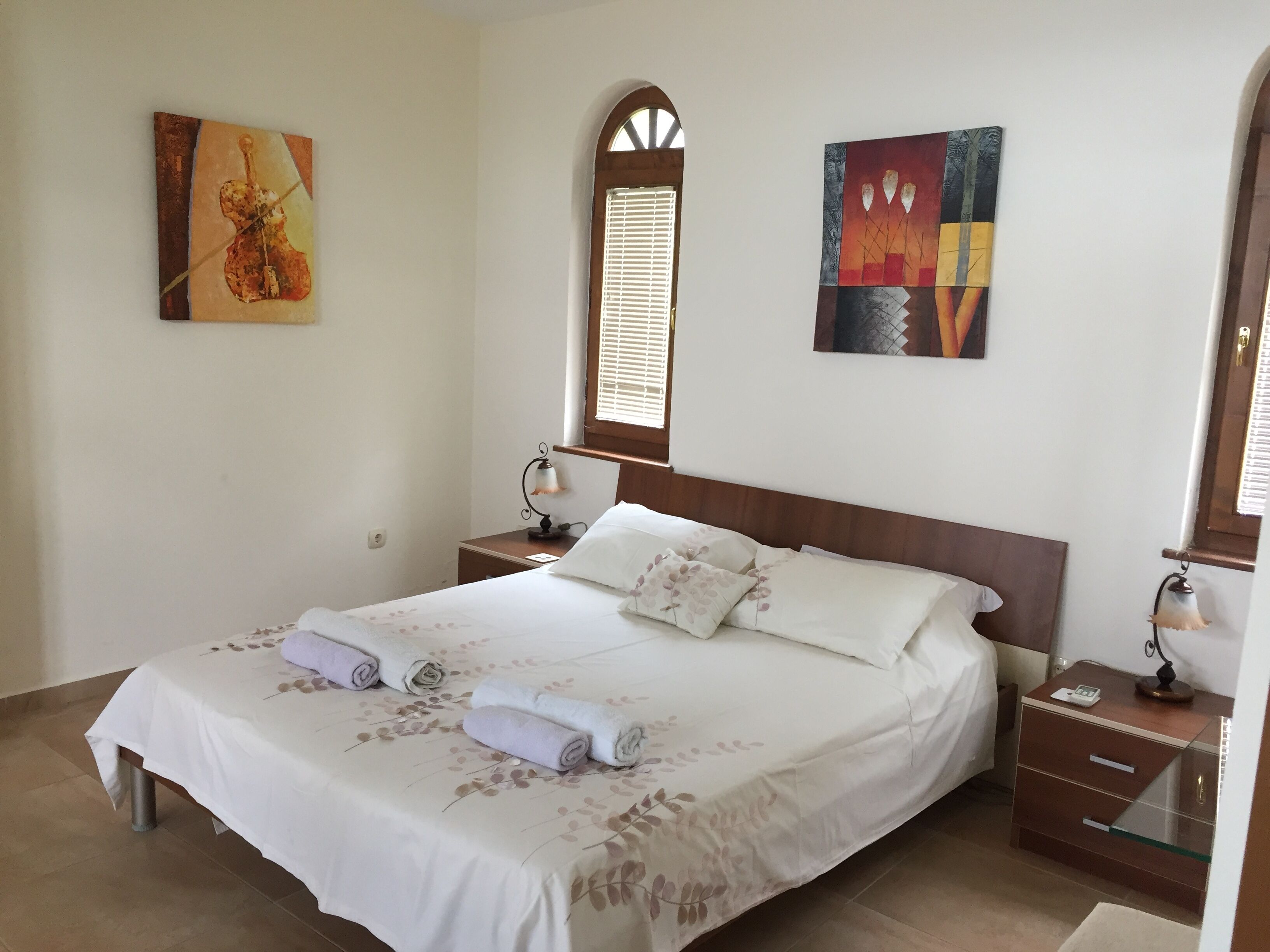 A neatly made bed with floral bedding, a wooden headboard, and two bedside tables with lamps.